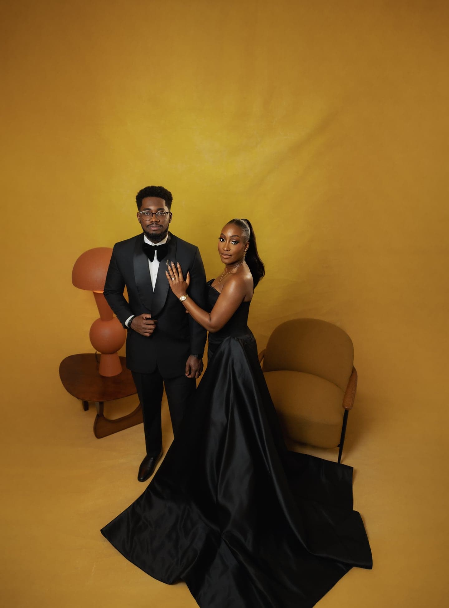 Pulfer & Geraldine in black-tie, standing together against a mustard backdrop